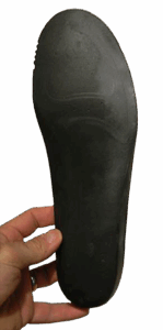 A hand is holding a black shoe insole, viewed from the bottom side.