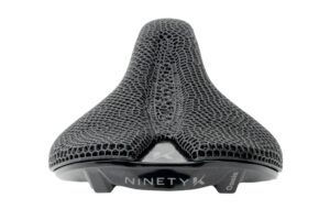 A close-up view of a black bicycle saddle with a textured surface and "Ninety K Oasis" printed on the base.