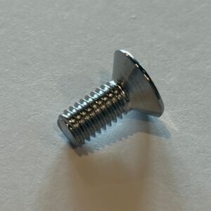 A metal flat-head screw with a threaded shaft is lying on a white surface, positioned at an angle.